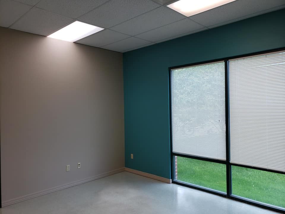 An empty room with blue walls and two windows