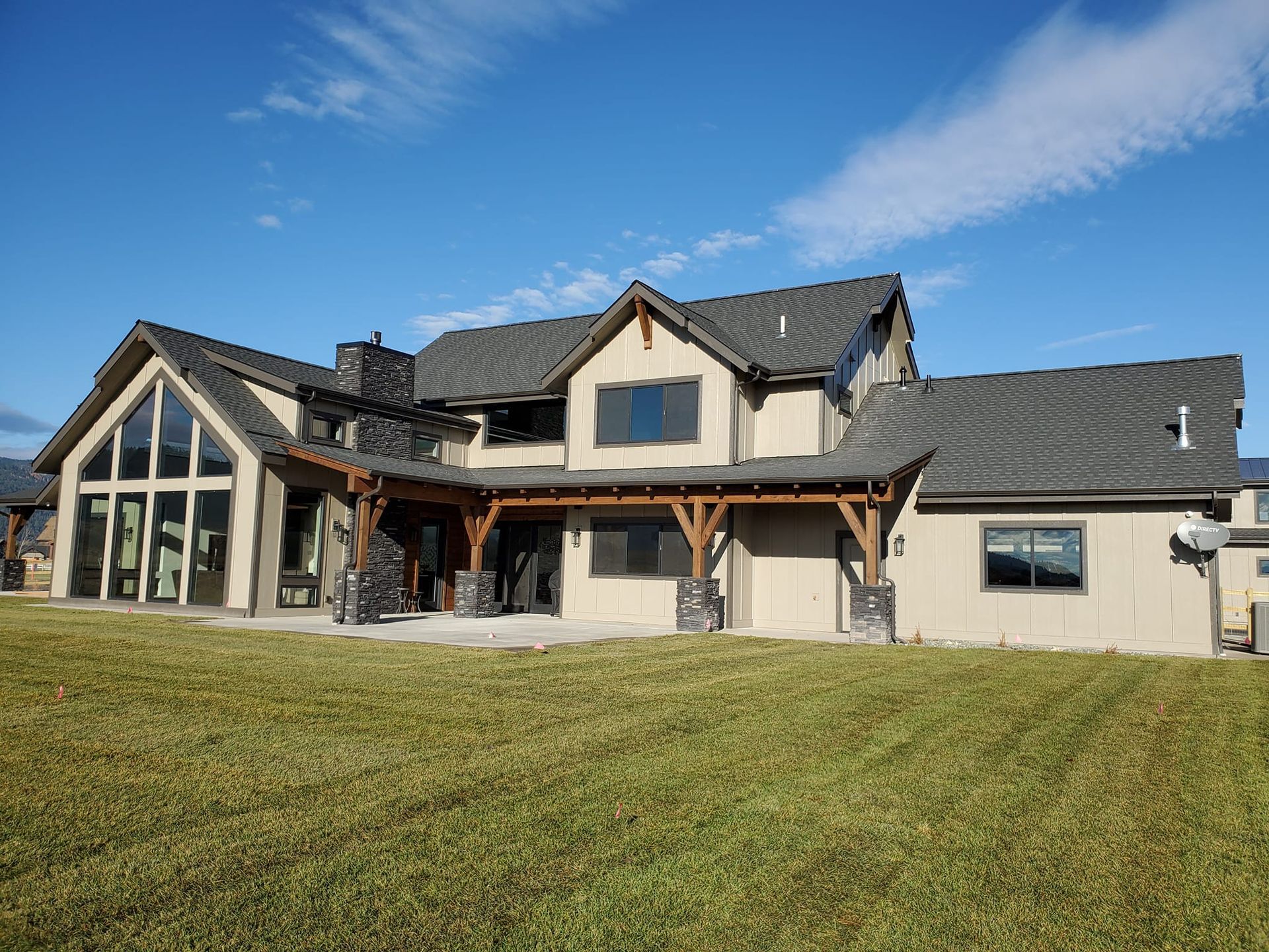 A large house with a lot of windows is sitting on top of a lush green field.