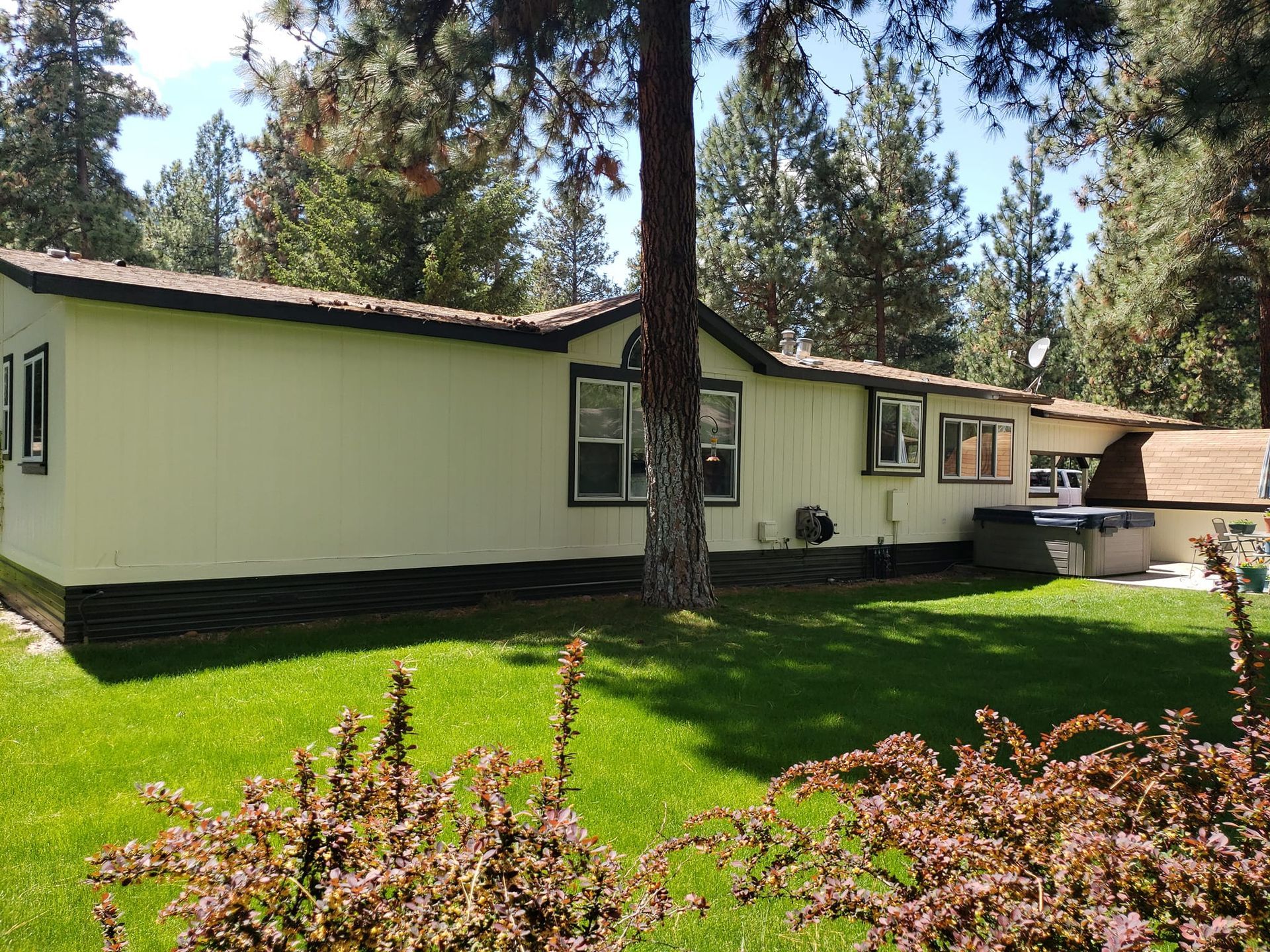 A mobile home is sitting on top of a lush green lawn surrounded by trees.