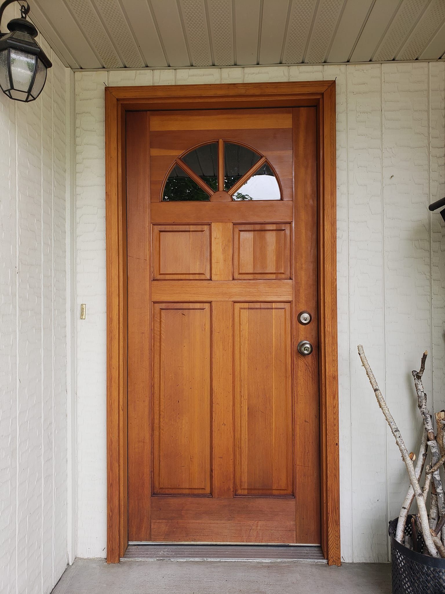 A wooden door with a glass window is on a white brick wall.