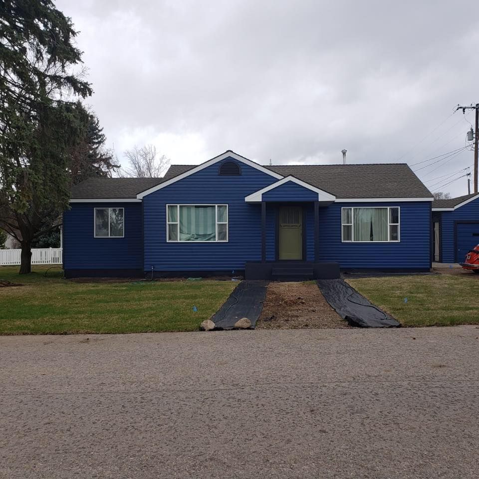A blue house with a red car parked in front of it