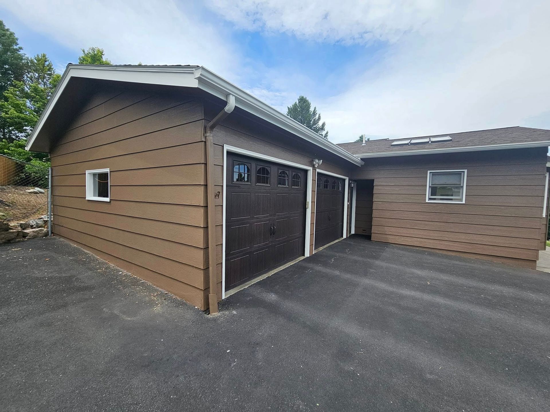 A brown house with two garage doors and a driveway