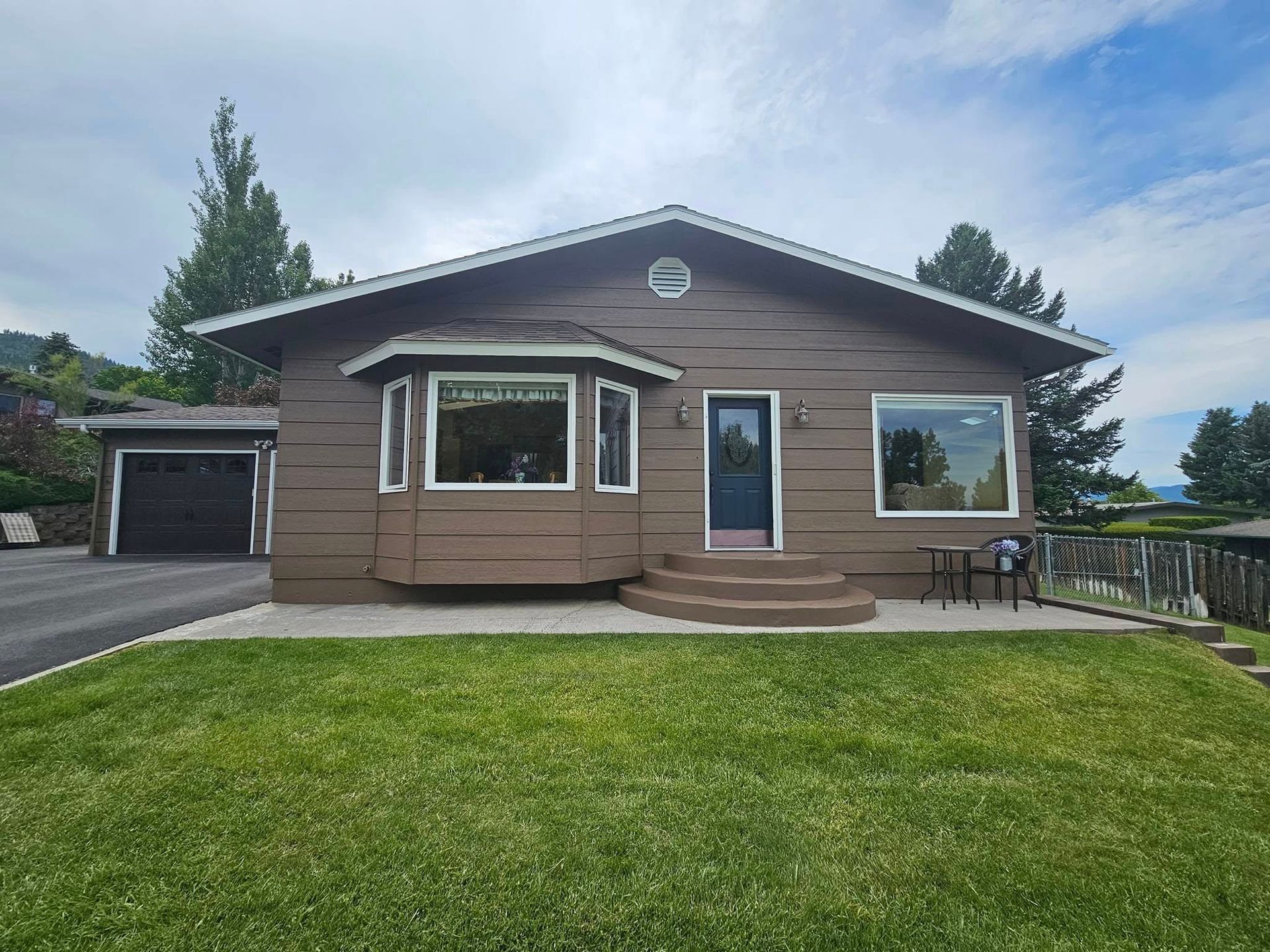 A brown house with a large lawn in front of it.