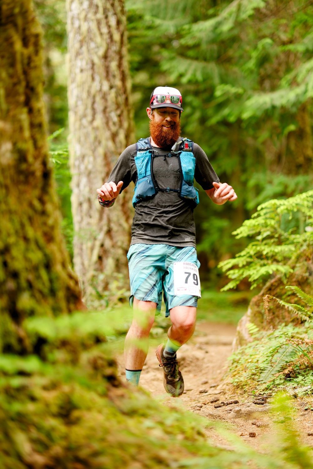A man is running on a trail in the woods.