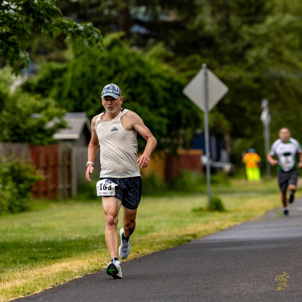 A man is running on a bridge with the number 211 on his shirt.