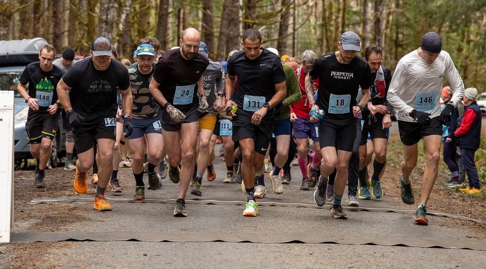 A man is running down a trail in the woods.