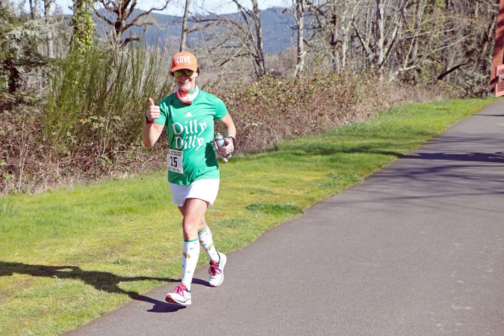 A woman is running on a trail in the woods.