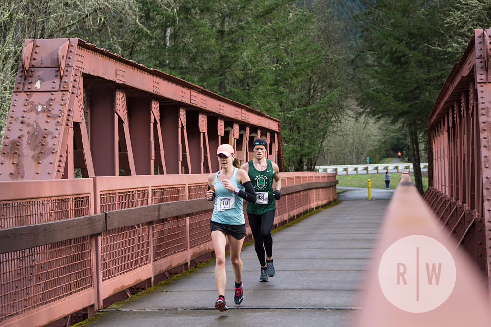 Two women are running a marathon on a bridge.