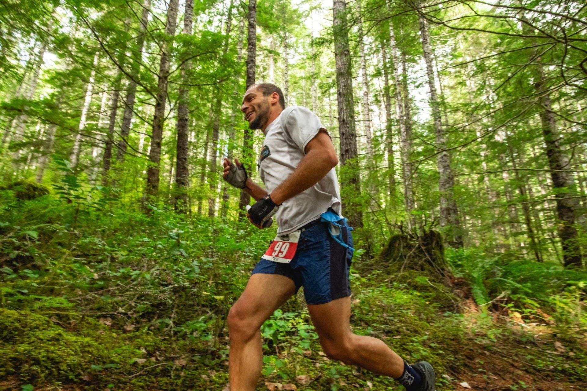 A man is running through a forest on a trail.