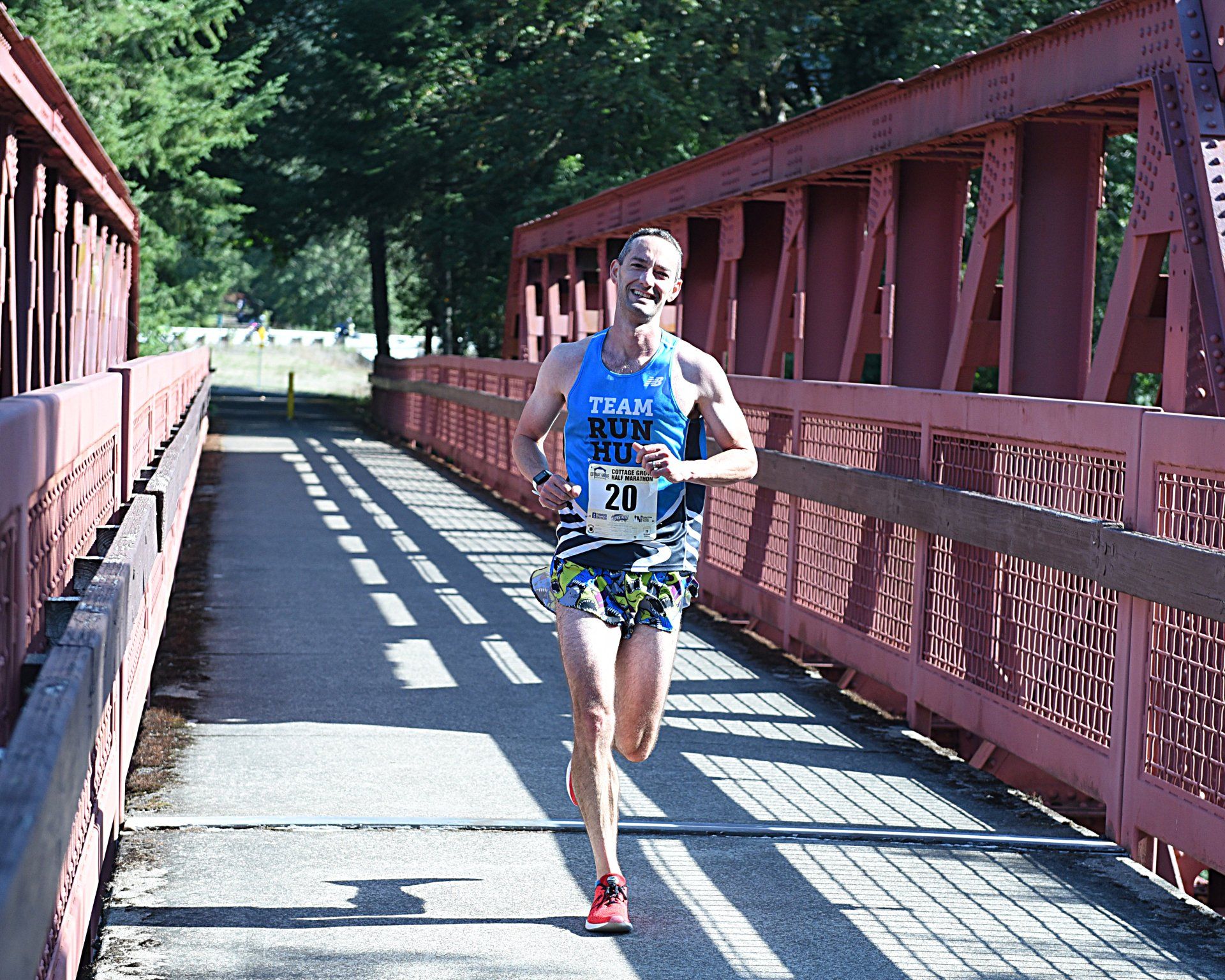 A man is running on a bridge with the number 211 on his shirt.