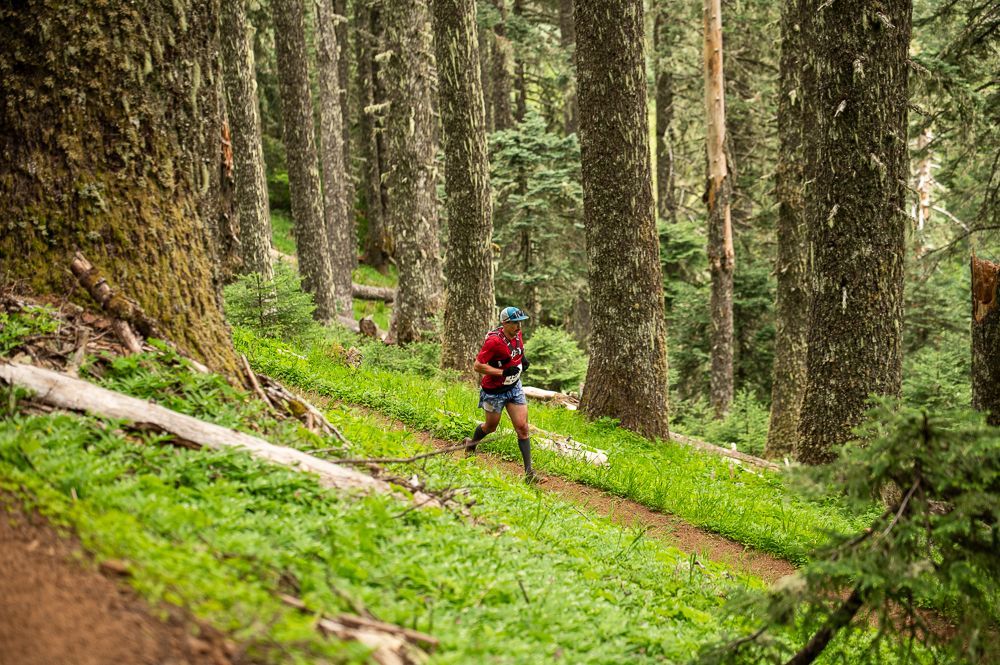 A man is running on a trail in the mountains.