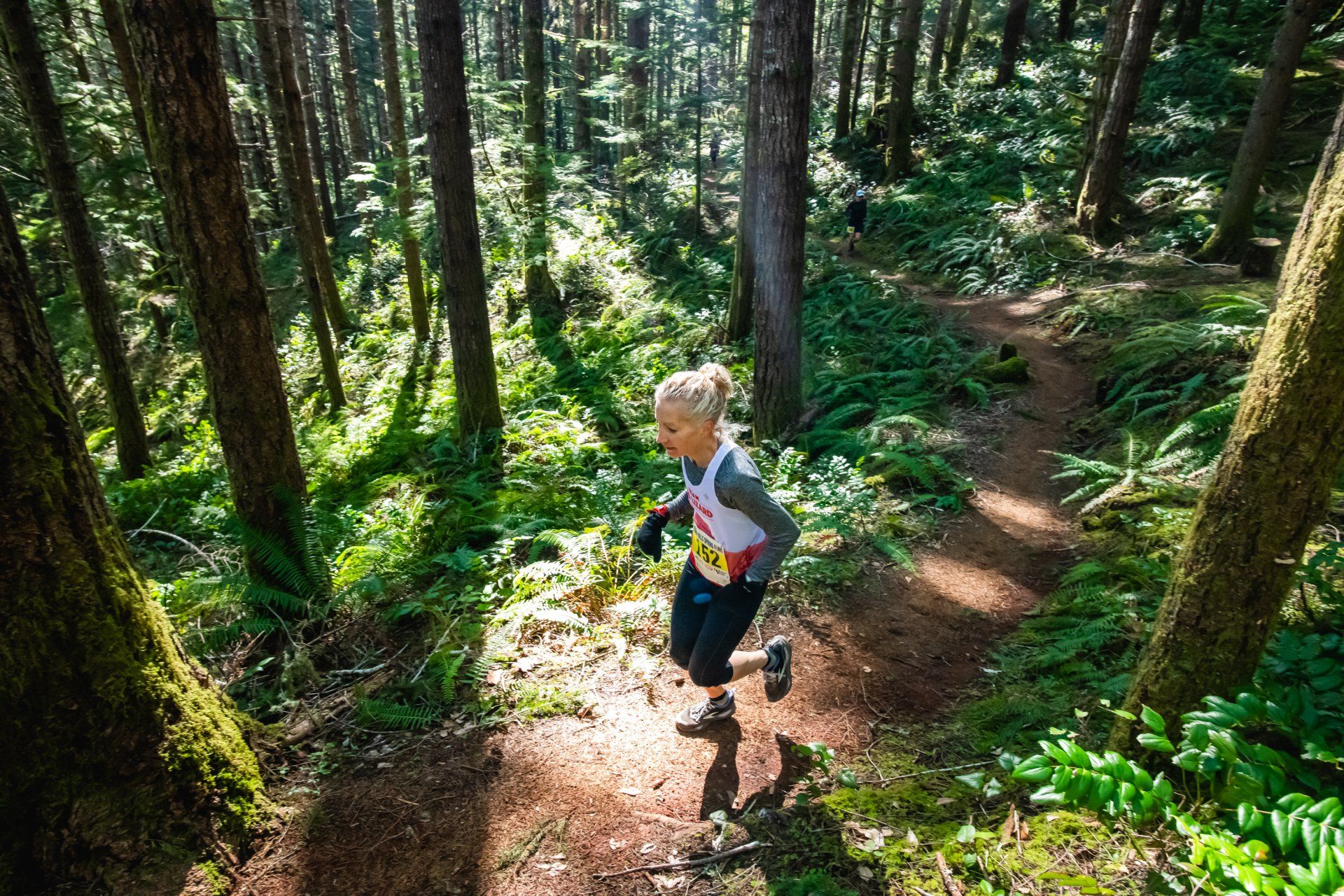 A person is running down a trail in the woods.