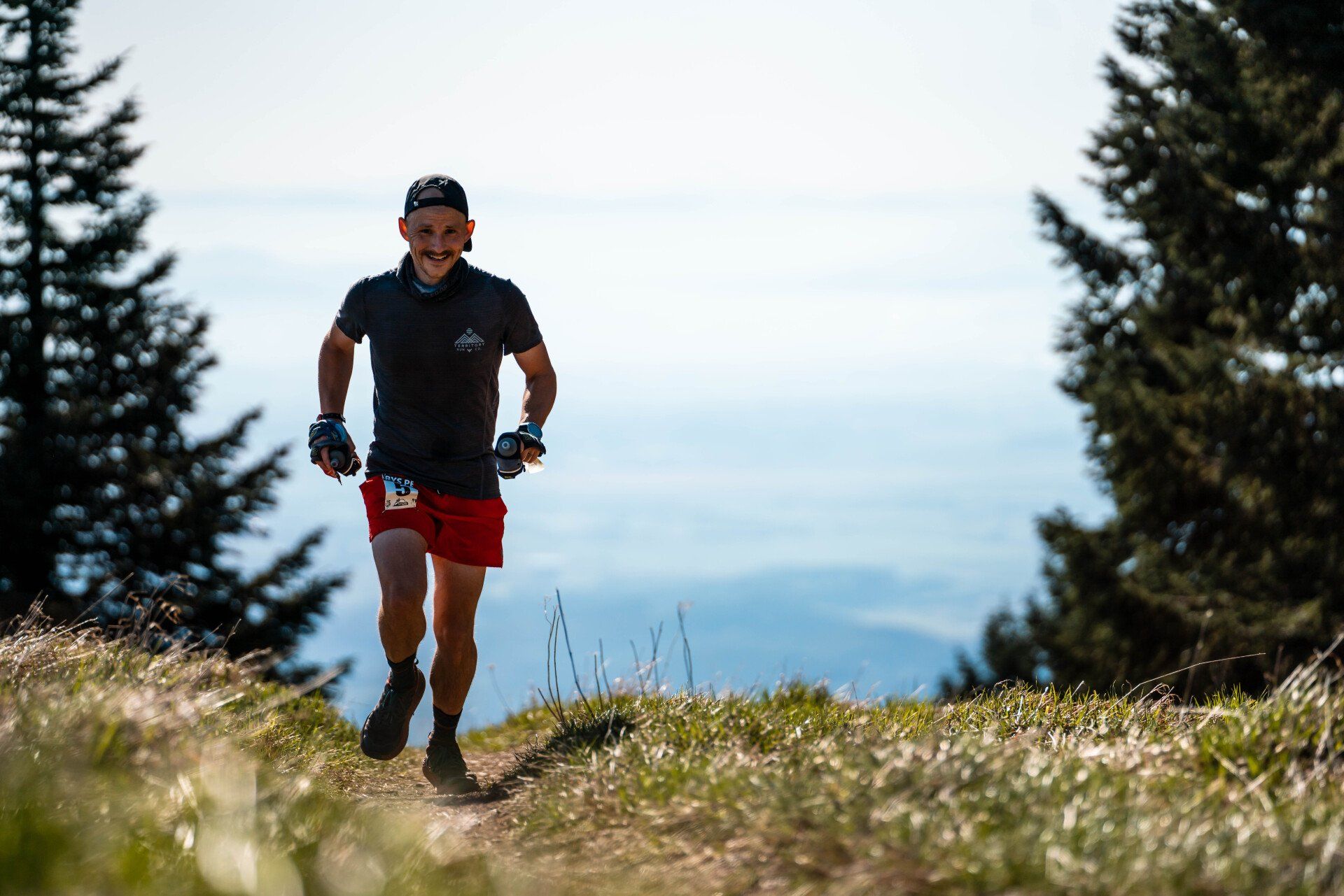 A man is running on a trail in the mountains.