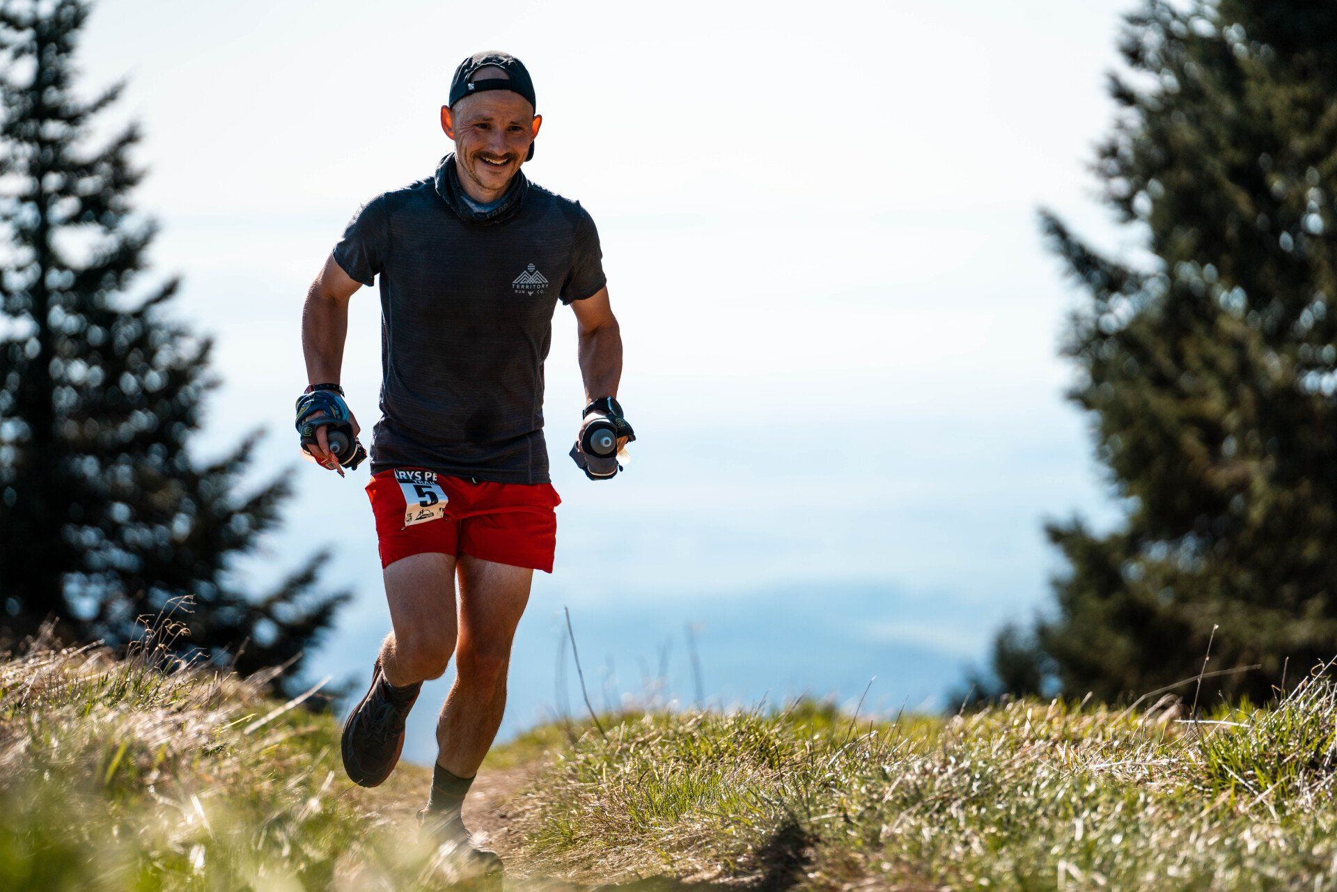 A man is running on a trail in the woods.