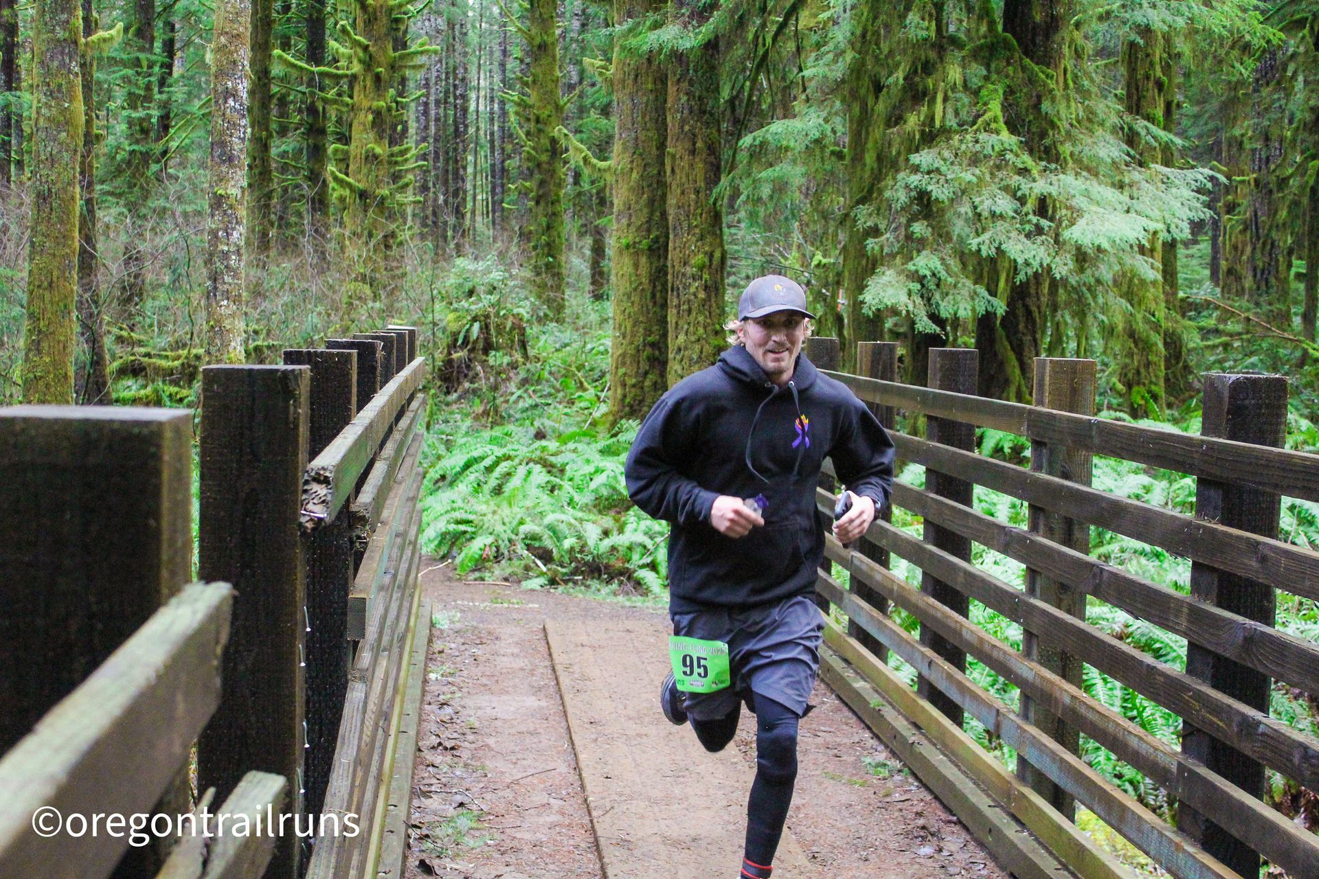 A man is running on a wooden bridge in the woods.