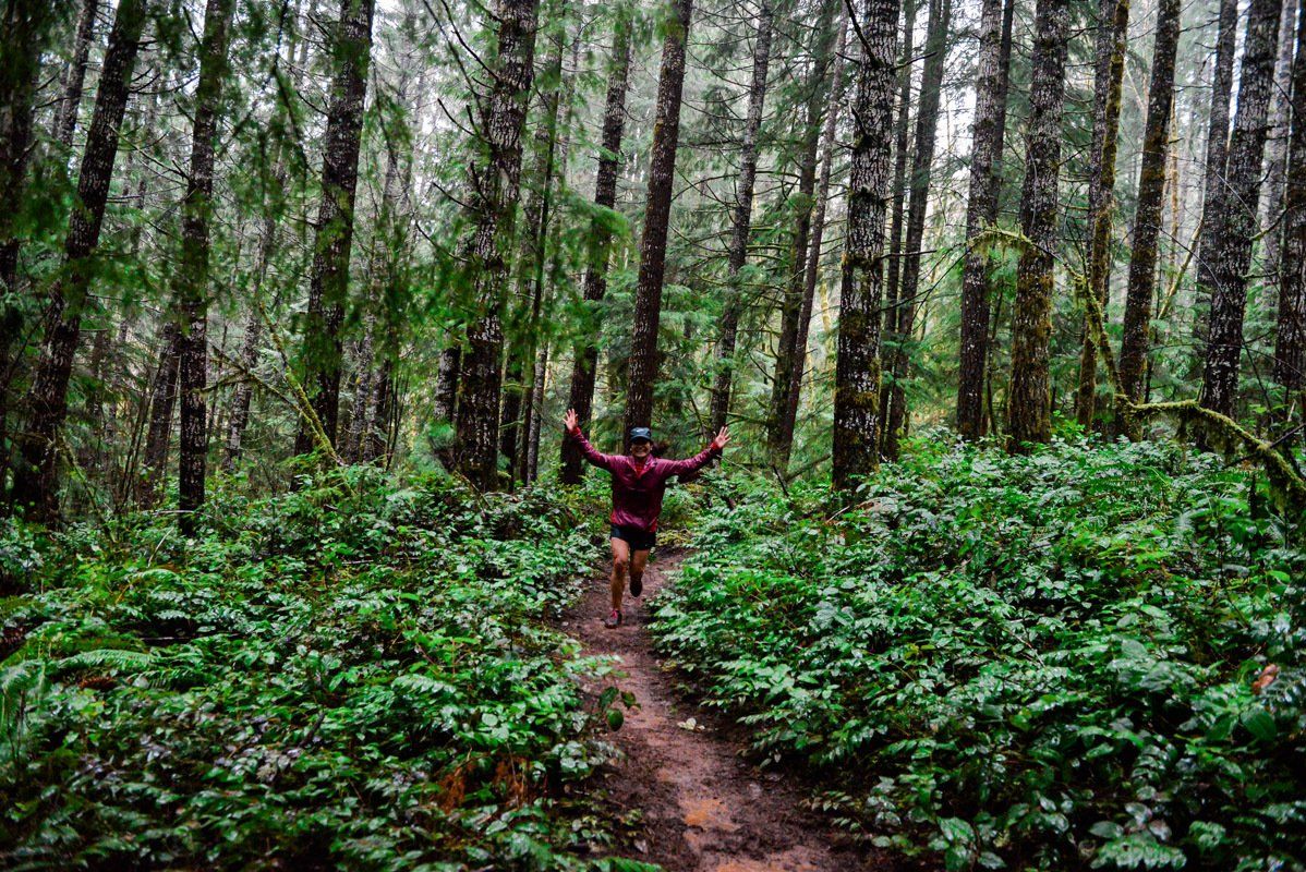 A person is running through a lush green forest.