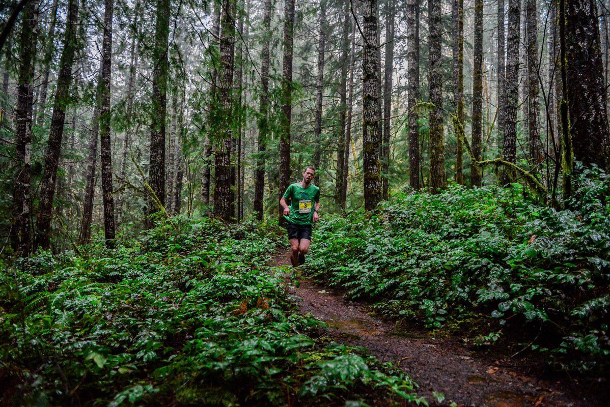 A man is running through a lush green forest.