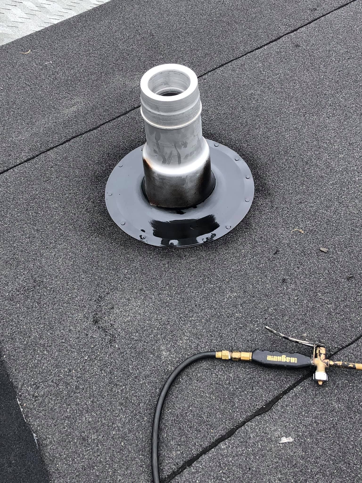 A roof vent pipe with a circular base, likely for plumbing. A small torch lies nearby.