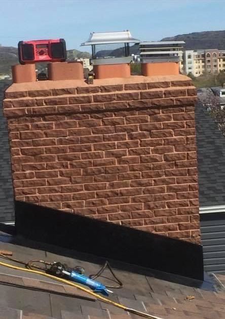 Brick chimney with three flue caps on a rooftop. A red level sits atop the chimney.
