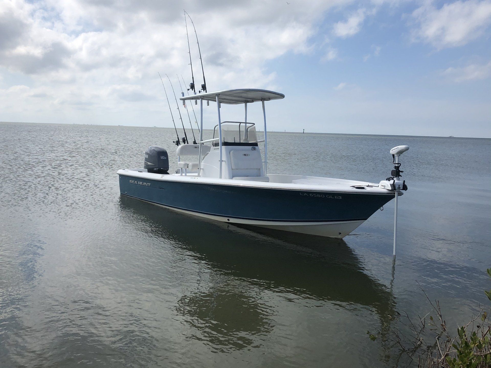 A blue and white boat is floating on top of a body of water