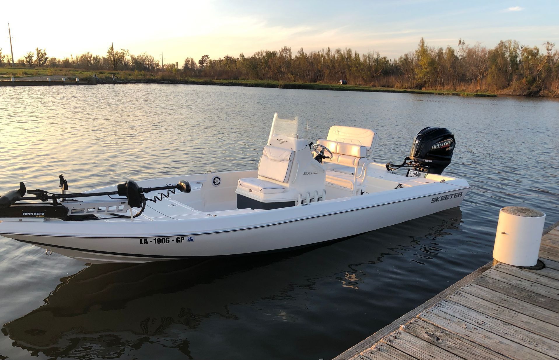 A white boat is docked at a dock in the water.