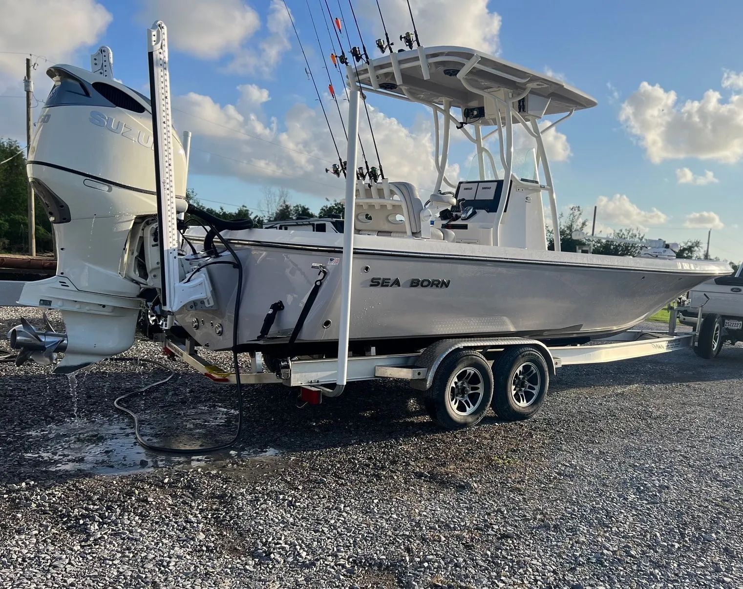 A boat is parked on a trailer in a gravel lot.