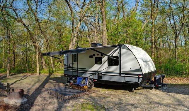 A rv is parked in a campground in the woods.