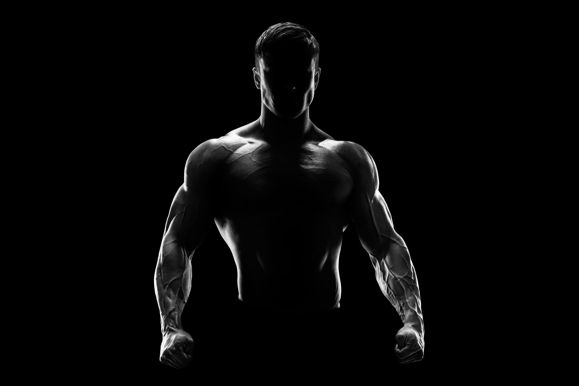 Muscular torso, arms flexed, dark silhouette against black background.