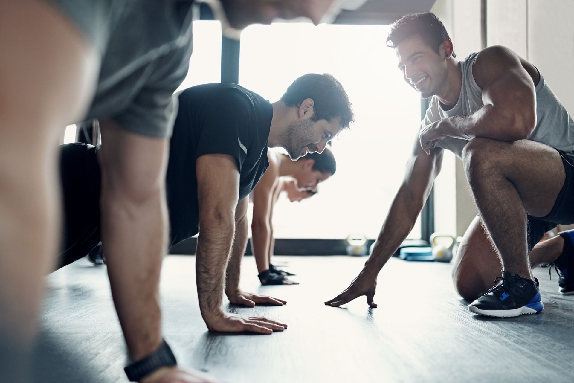 People doing push-ups in a gym, with a trainer.