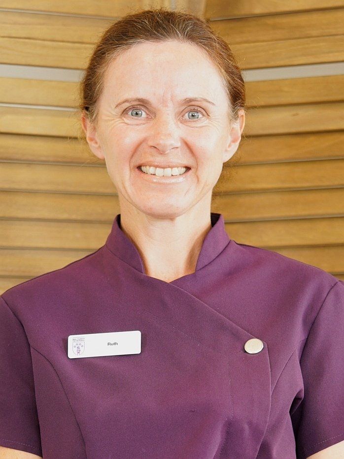 A woman in a purple uniform is smiling for the camera.