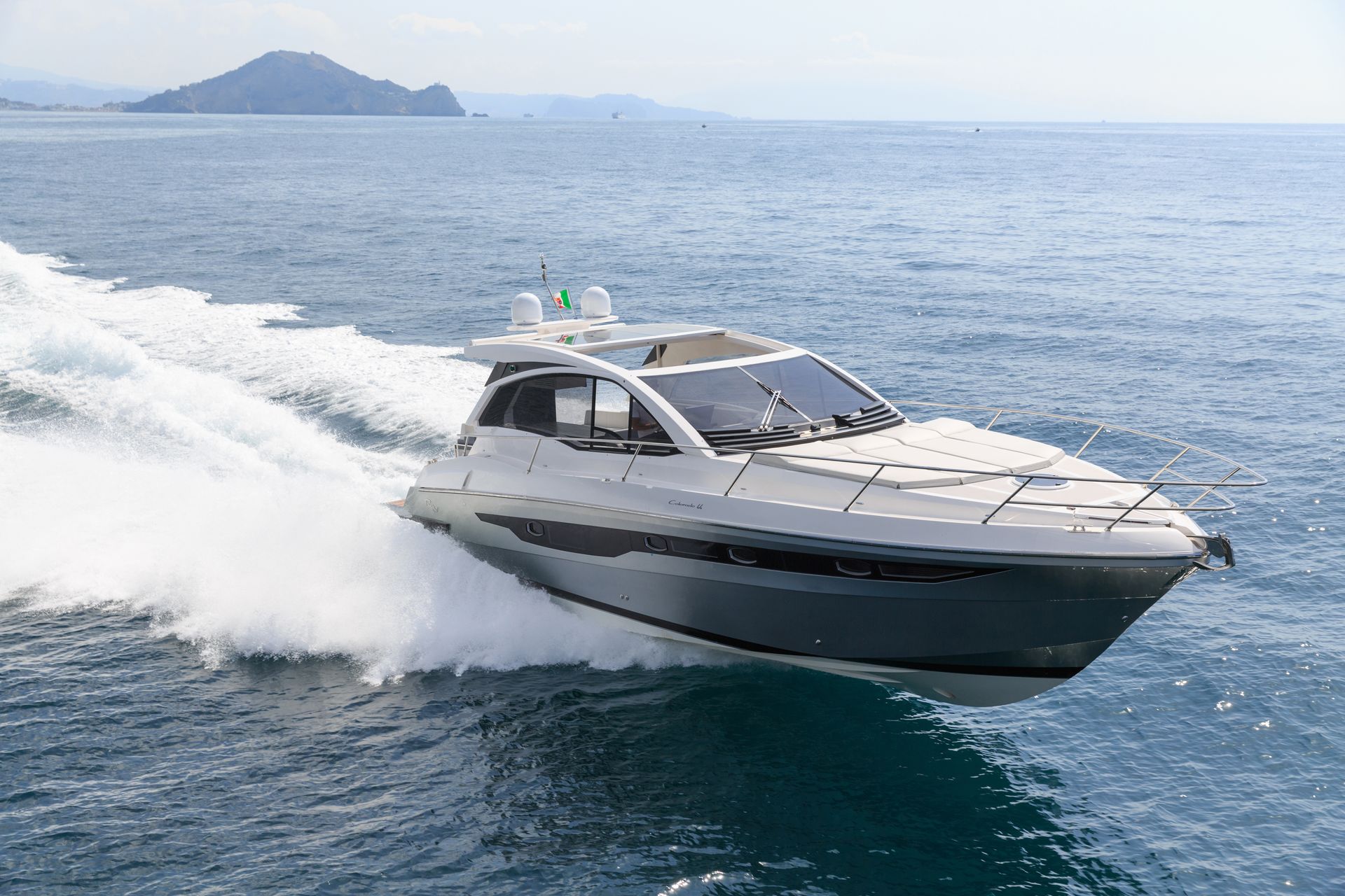 A sleek motor yacht speeds across open water with waves trailing behind it.