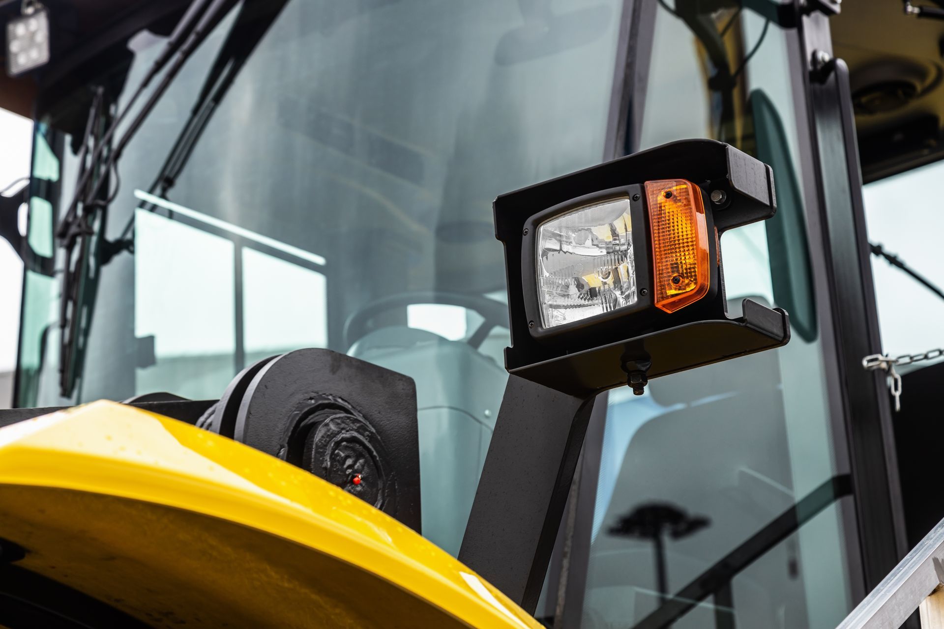 Yellow construction vehicle: headlight and turn signal attached to the cab.