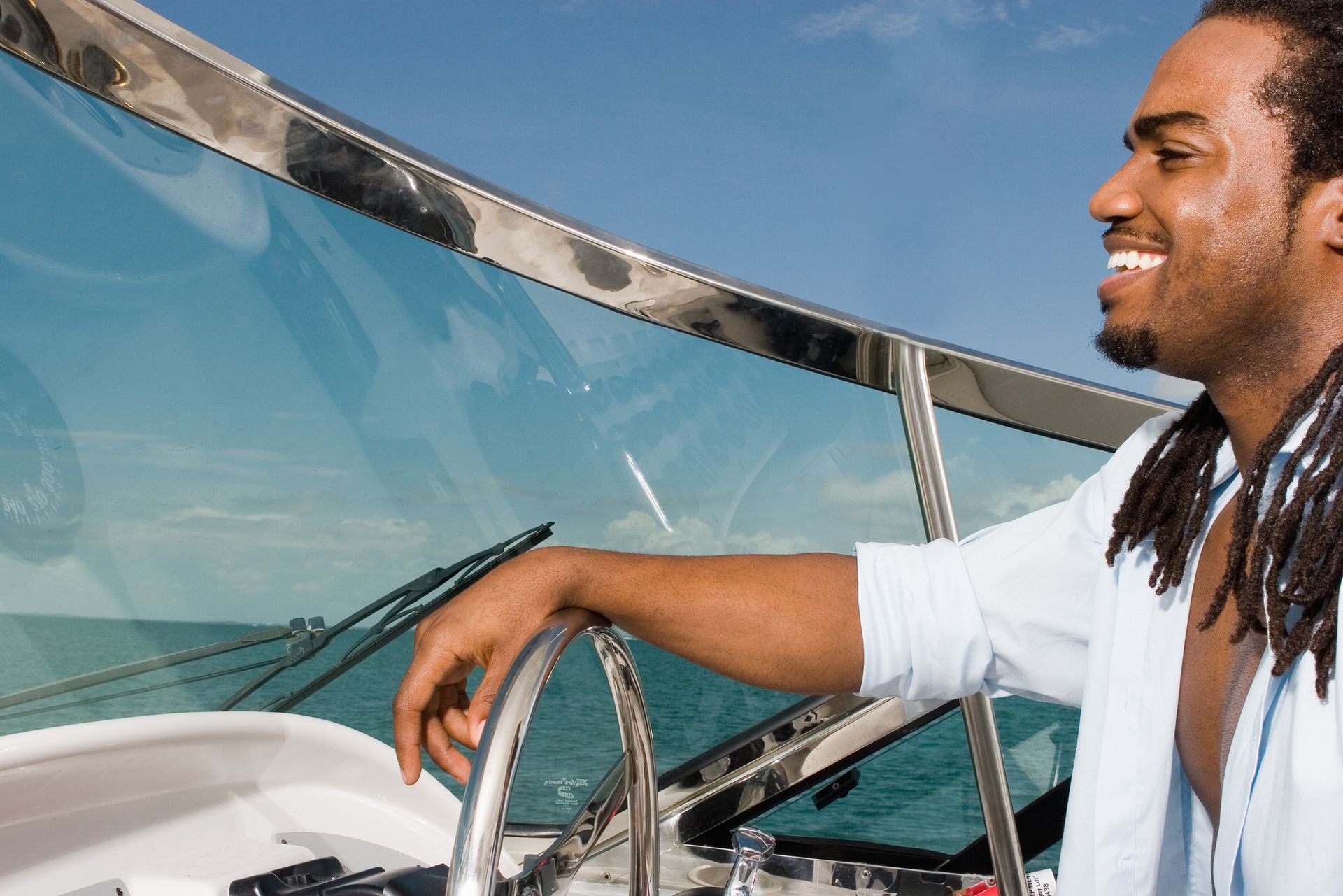 Young man at wheel of boat, smiling and looking out the boat glass, side view. Young man at wheel of boat, smiling and looking out the boat glass, side view.