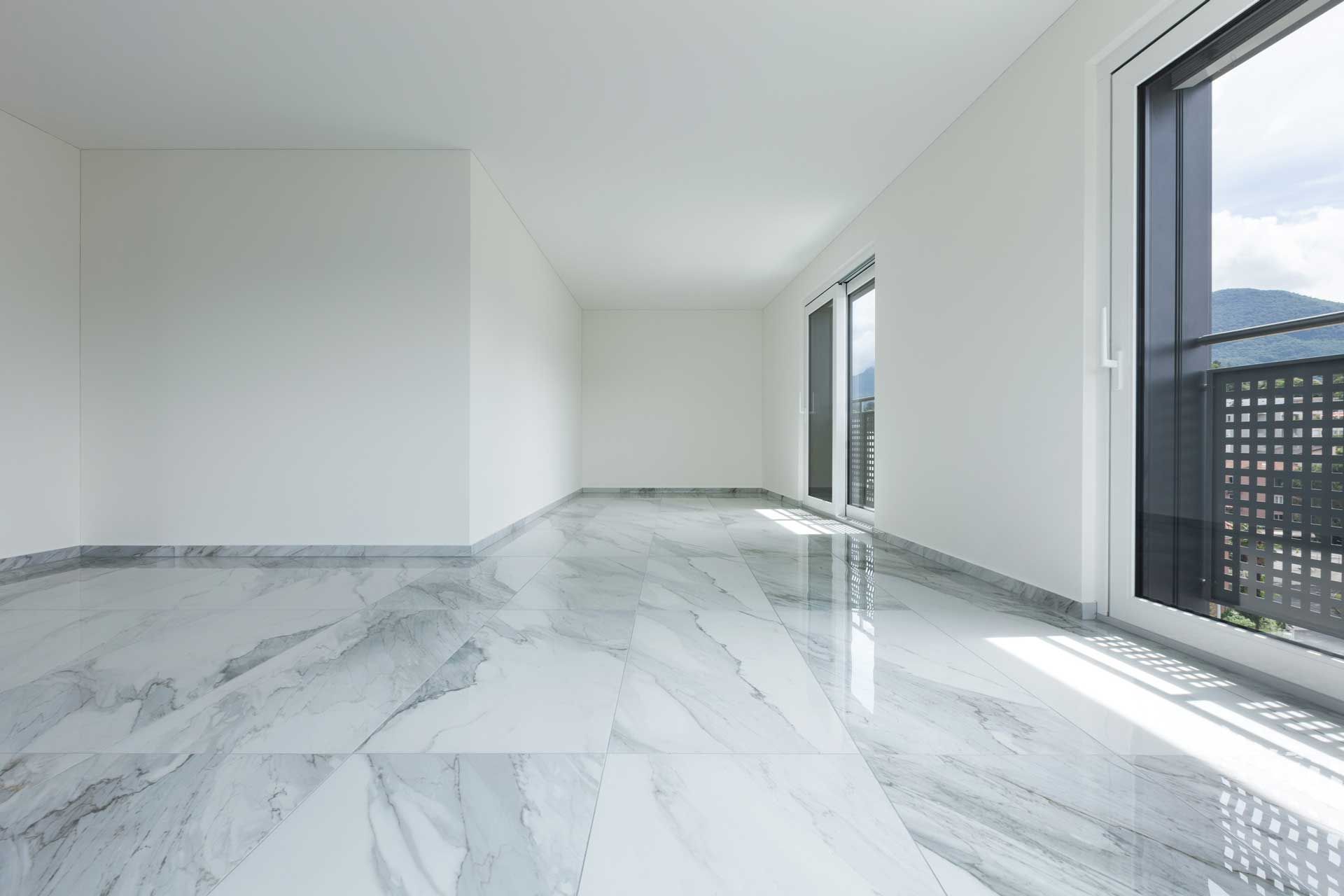 An empty room with a marble floor and large windows.