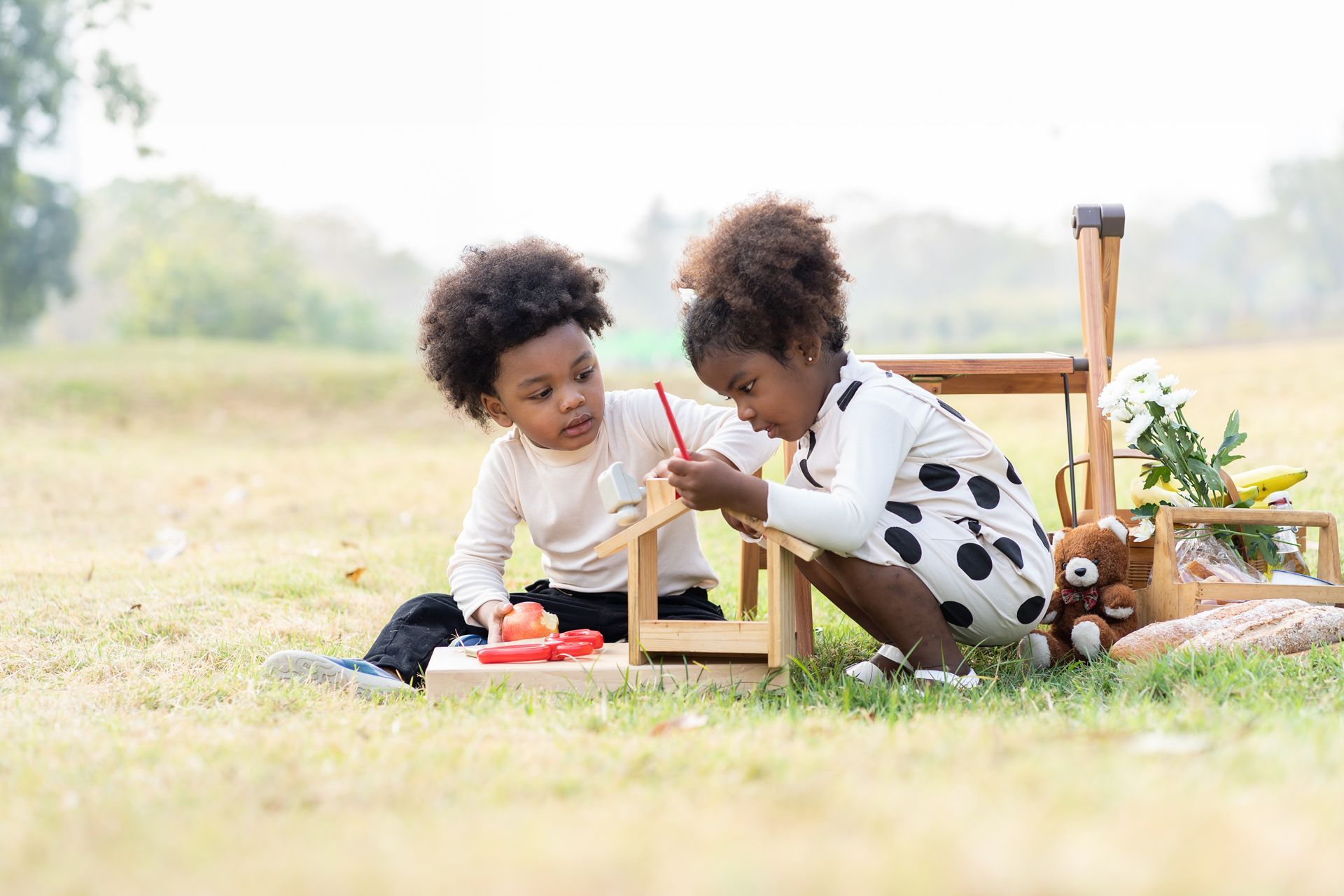 A boy and a girl are sitting on the grass playing with toys