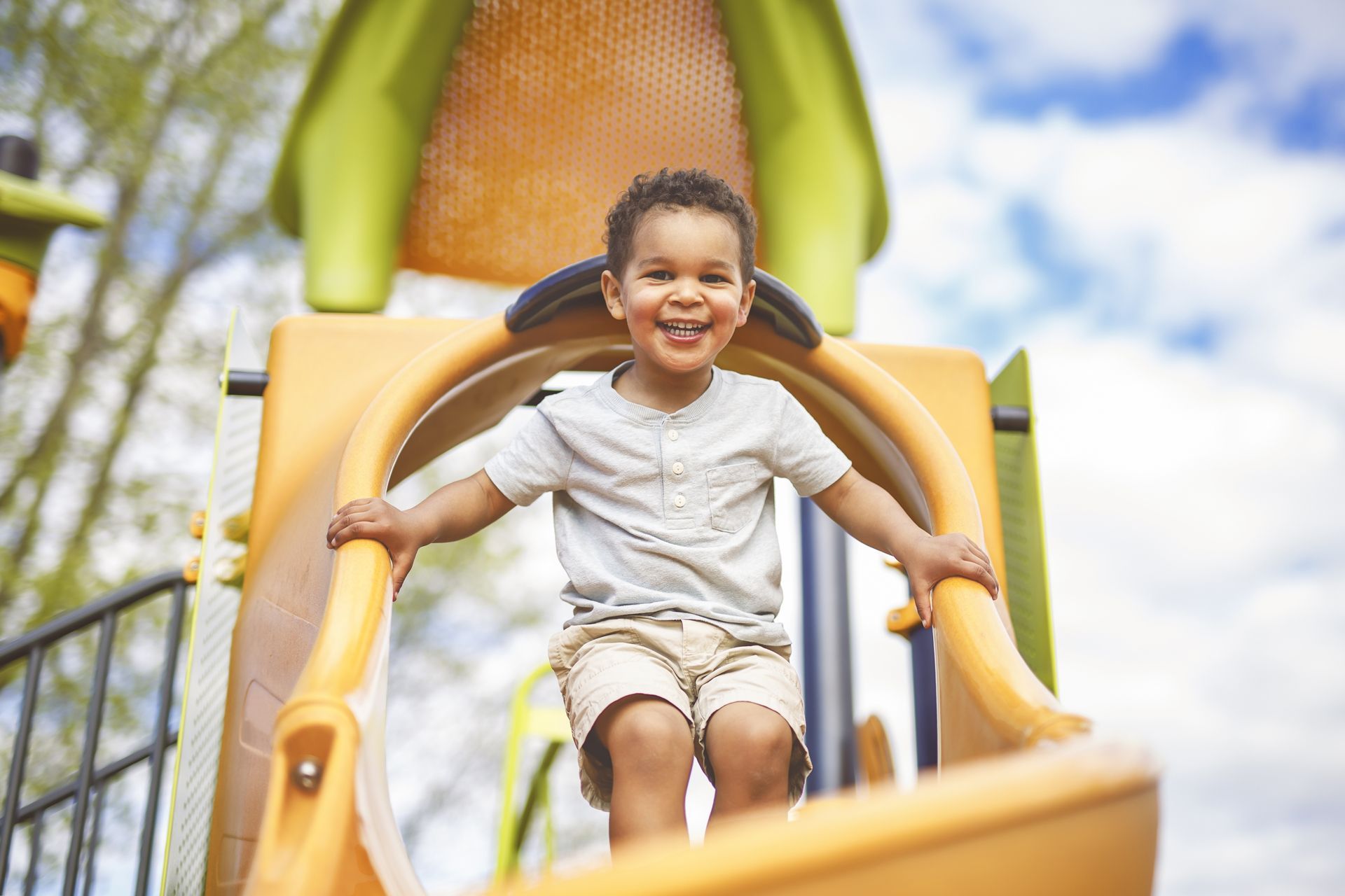 A young boy is sitting on a slide at a playground