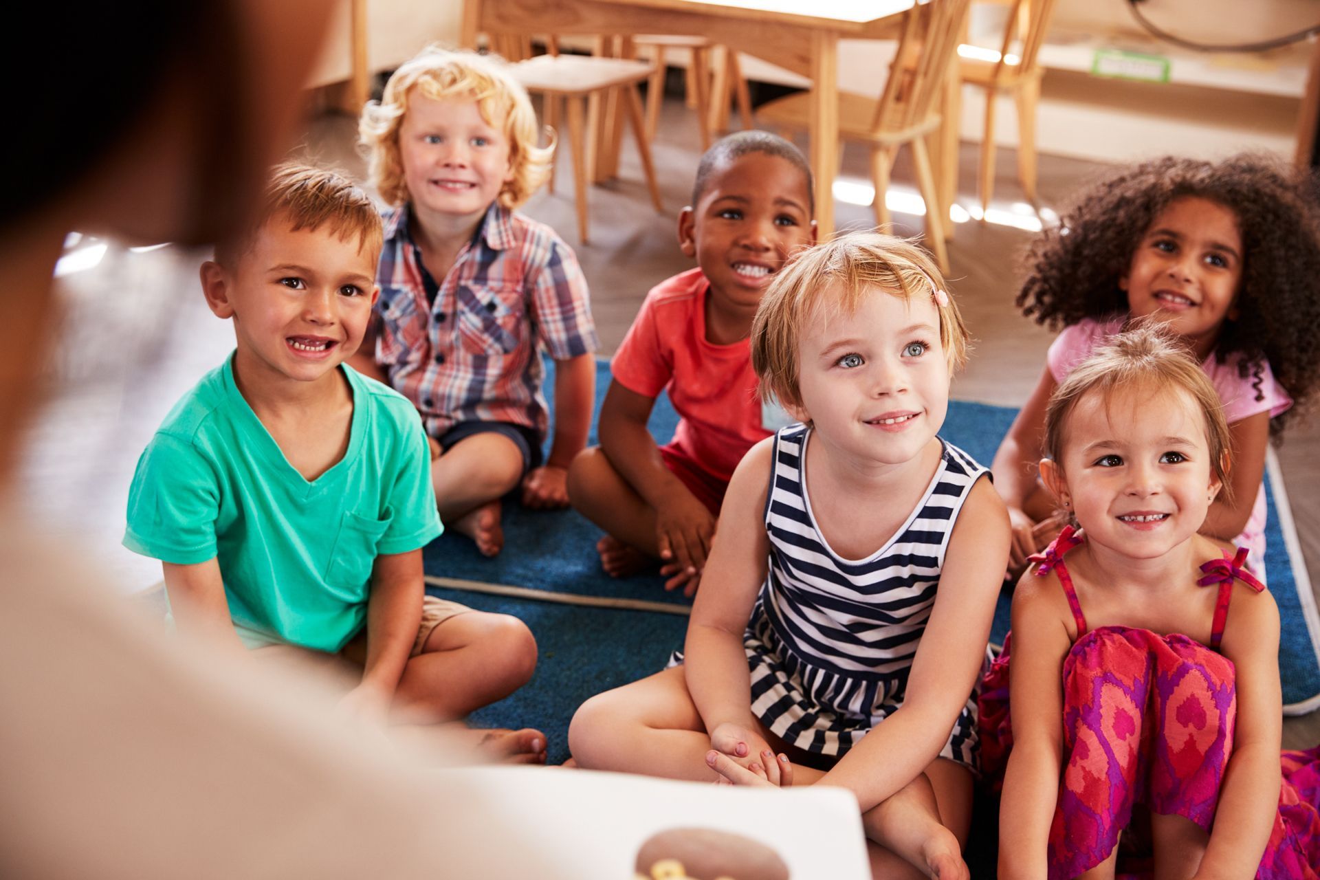 A group of children are sitting on the floor listening to a story