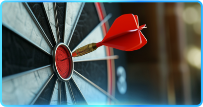 People at a table in an office, discussing work with laptops, papers, and plants.