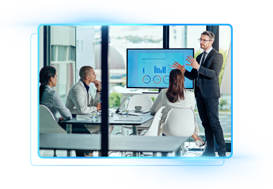 Four people in an office looking at a laptop. The man in blue is typing while others observe.