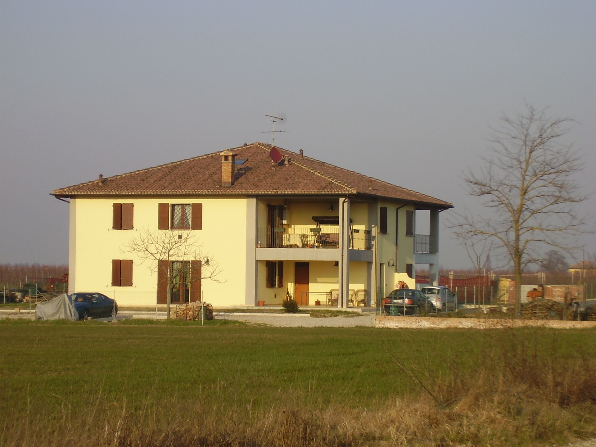 Una casa gialla con il tetto marrone si trova in mezzo a un campo erboso