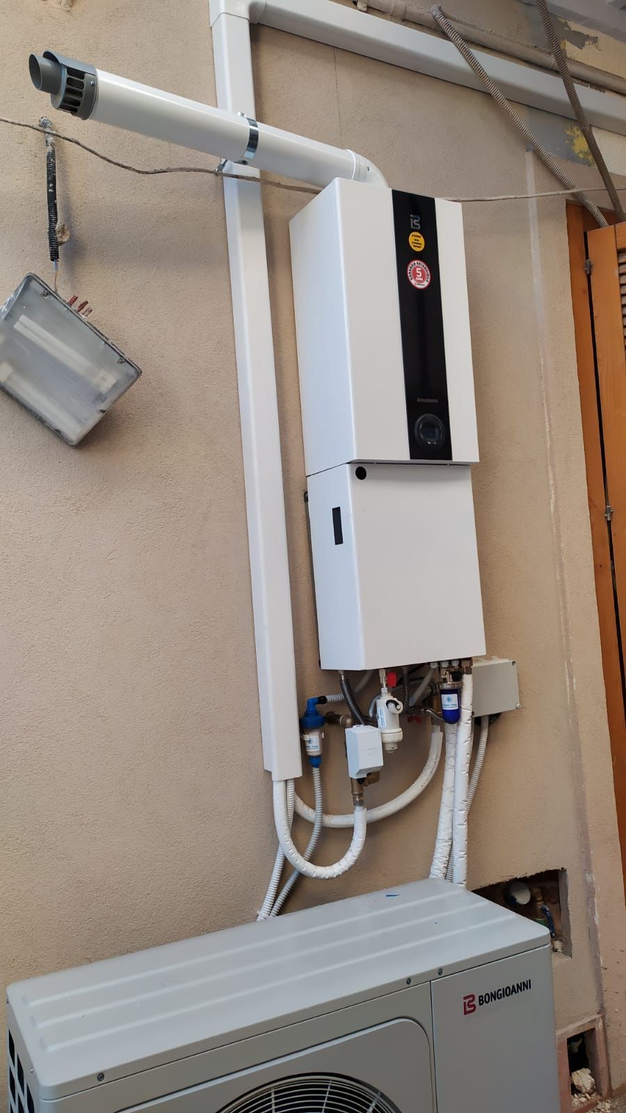 Una scatola bianca è appesa a una parete accanto a un ventilatore.