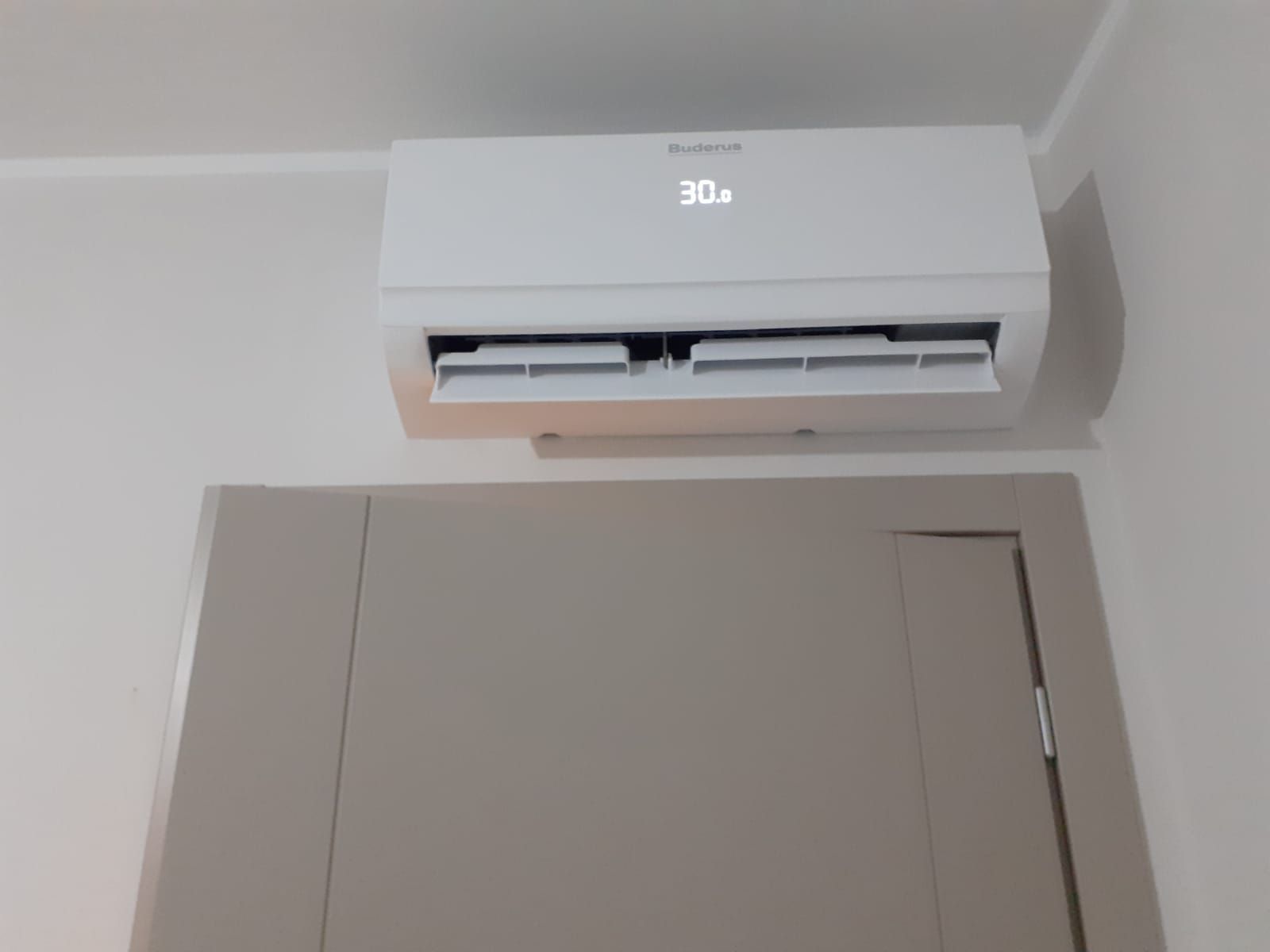Un condizionatore bianco è montato sulla parete sopra una porta.