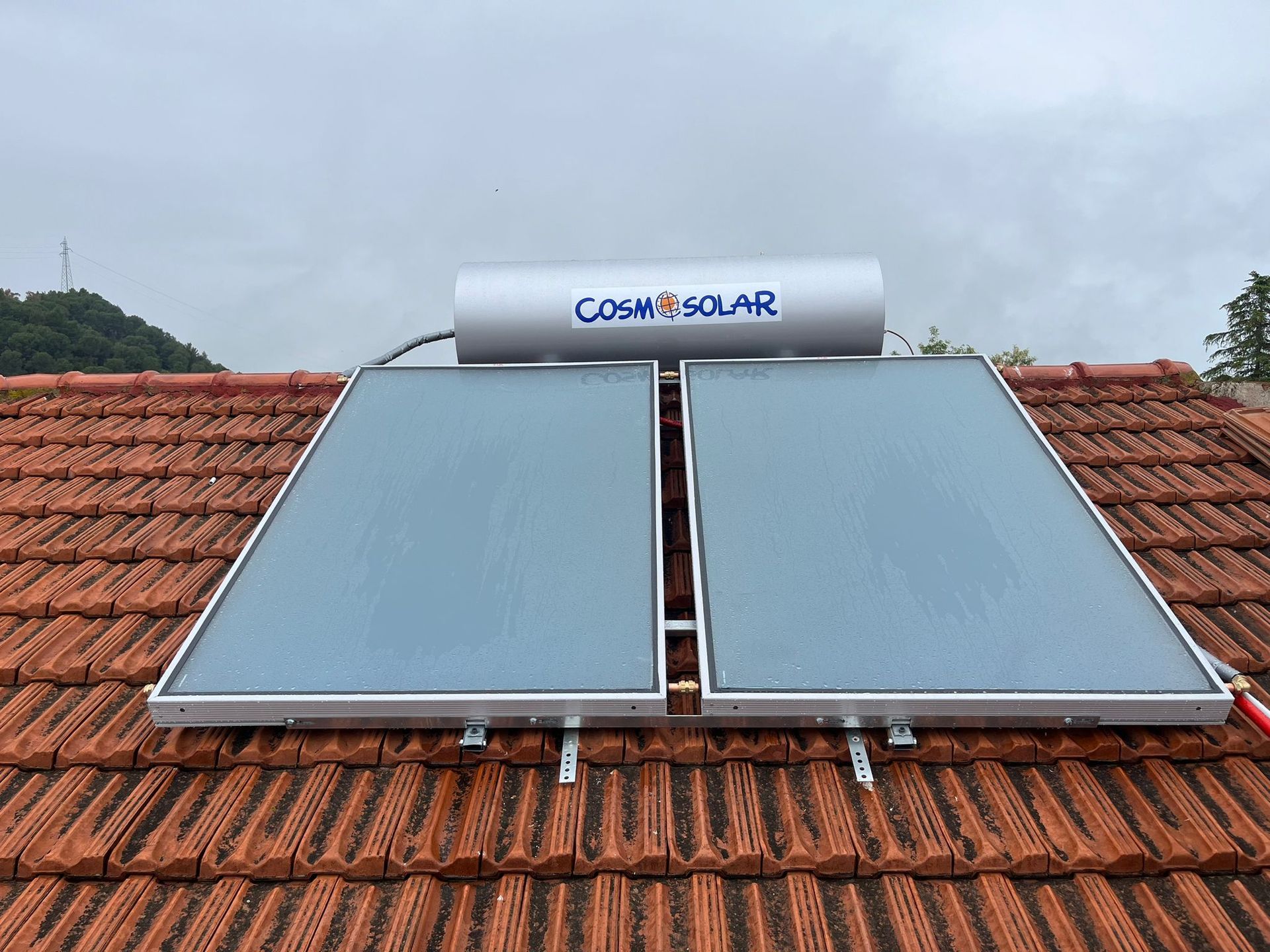Uno scaldabagno solare è posizionato sopra un tetto di tegole.