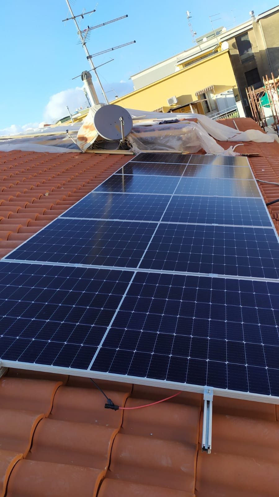 Una fila di pannelli solari è posizionata sopra un tetto di tegole.