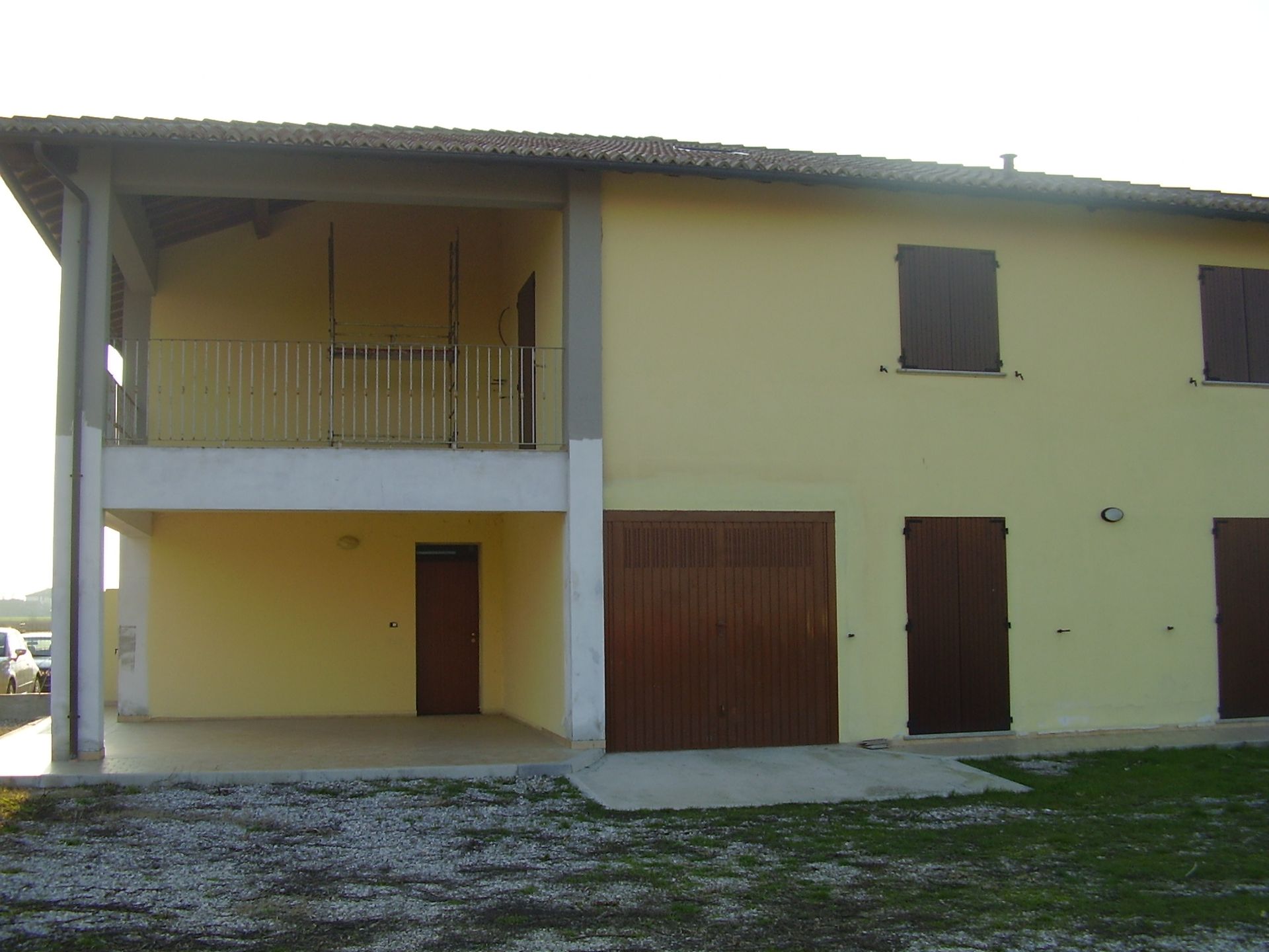 Una casa gialla con balcone e porte da garage