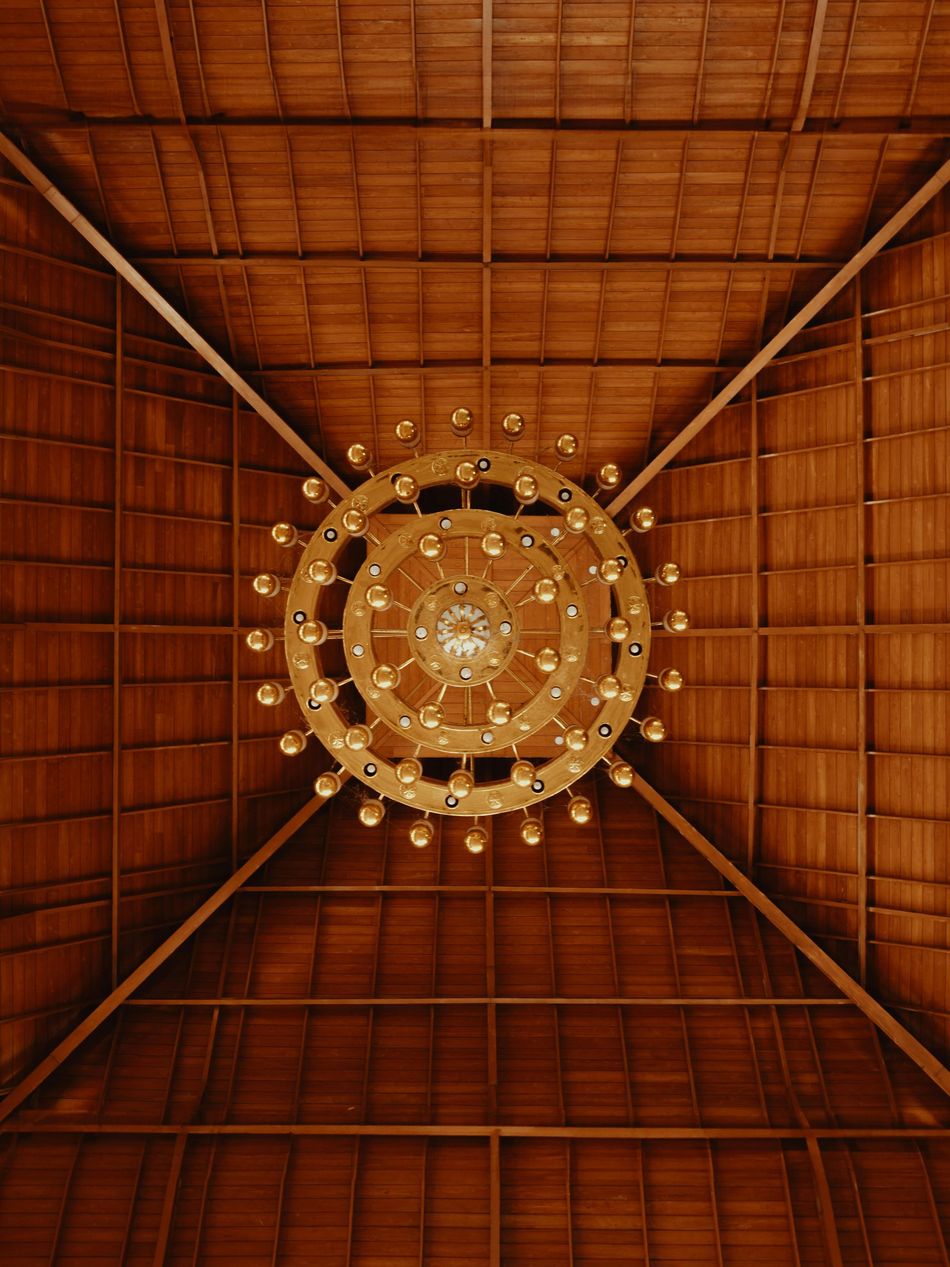 Looking up at a chandelier hanging from a wooden ceiling.