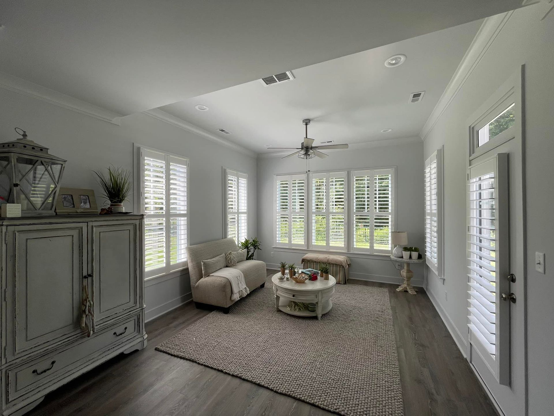 A long window seat with cushions and blue pillows, overlooking a scenic waterfront view with a wooden deck.