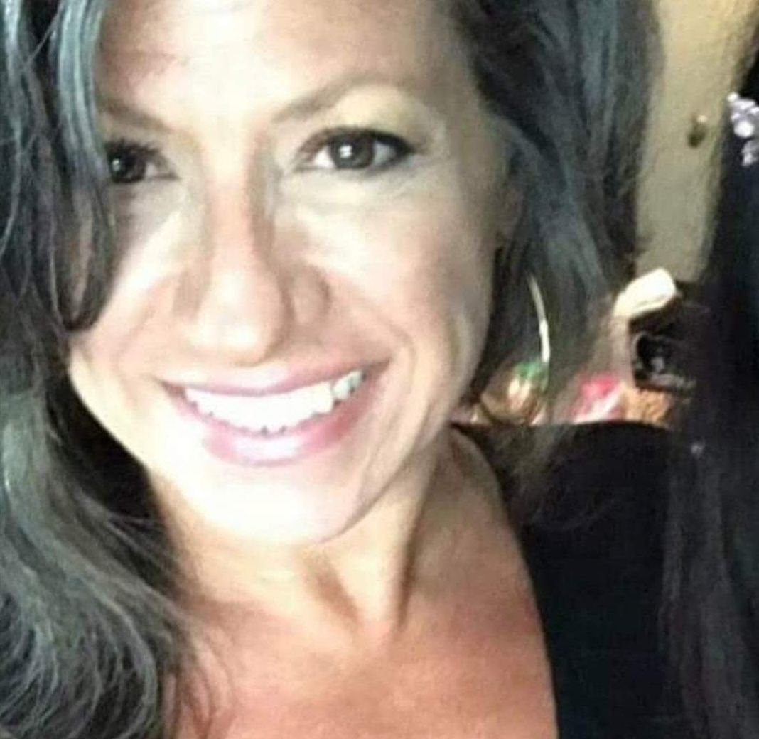 A woman with gray hair is smiling for the camera.