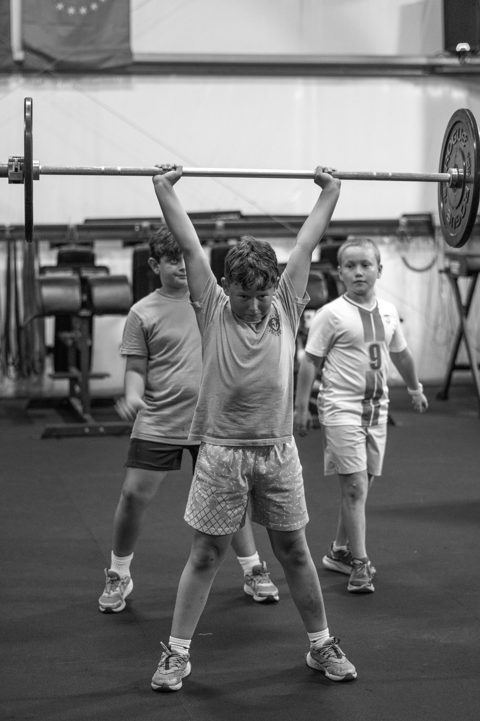 A person wearing a blue long-sleeve shirt and tan shorts bends over to lift a barbell at Crossfit Anchor Down