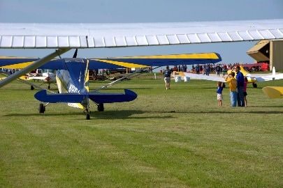 A blue and yellow plane is parked in a grassy field